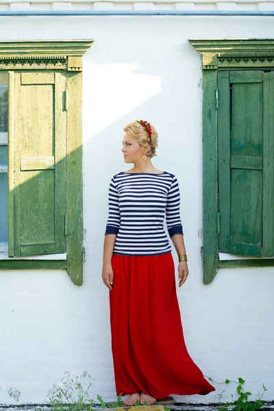 Beautiful girl stands on background of rural house — Stockfoto