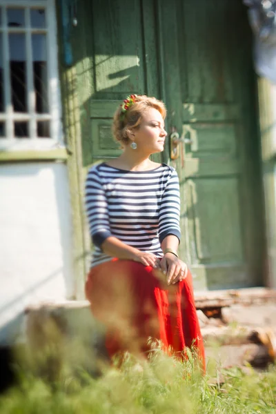 Beautiful girl sitting on steps of rural house — Zdjęcie stockowe