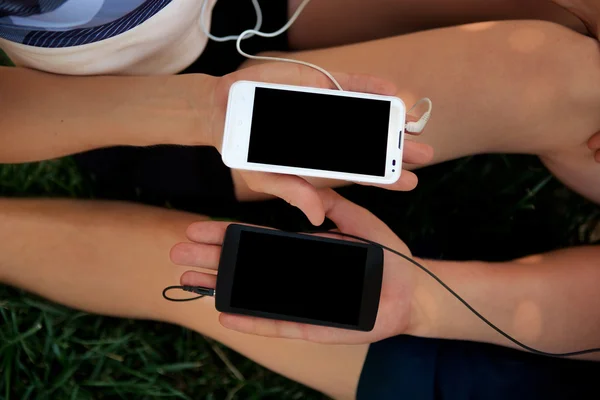 Close-up de mãos de menino e menina segurando dois smartphones — Fotografia de Stock
