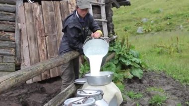 Çiftçi süt bir kova varil içine dökülen.