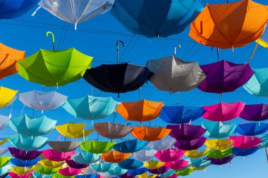 Colorful vibrant umbrellas hanging over the walking street for a festival on a blue sky sunny day (angle)