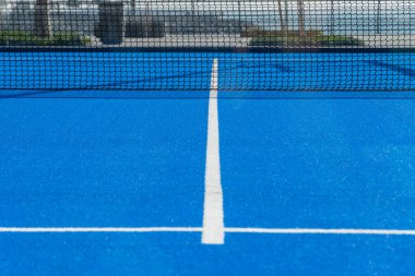 Parlak mavi tenis, raket topu ya da Pickleball saha manzarası açık havada siyah ağa doğru beyaz çizgi ile.