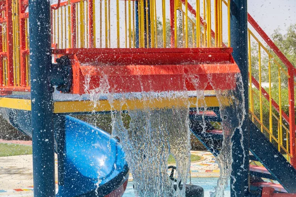 スプラッシュパッドの子供たちのための夏の楽しみは 明るい色の赤い噴水から下のプールに落ちる水で遊ぶ — ストック写真