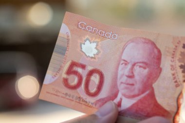 Elinizde Sör Wilfred Laurier 'ın 50 dolarlık kırmızı Kanada 50 dolarlık banknotunu tutuyorsunuz. Odaklanmamış arkaplan.