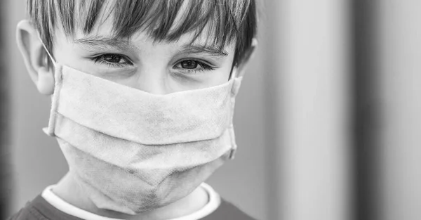 Un chico con un vendaje quirúrgico. Cuarentena por Coronavirus. Un chico con una máscara médica. Blanco y negro — Foto de Stock