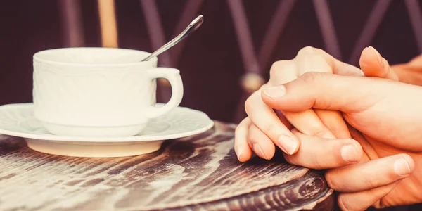 Female and man hands holding cup of coffee. Couple in love holding hands with coffee. Couple holding hands, a cup of hot coffee. Lovely couple holding cup of coffe in hands