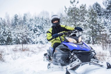 Man driving snowmobile in snowy forest. Man on snowmobile in winter mountain. Snowmobile driving clipart