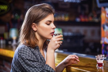 İçki içen genç ve güzel bir kadın. Barda ya da barda alkol bağımlılığı ve alkol konseptiyle izole edilmiş viski bardağı. Elinde bir bardak viski ya da rom tutan sarhoş kadın. Depresyondaki kadın