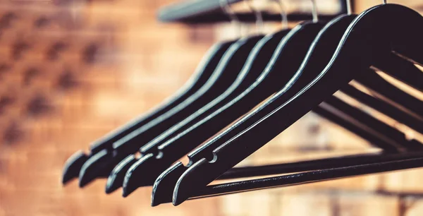 Wood hangers coat. Many wooden black hangers on a rod. Store concept, sale, design, empty hangers. Wooden coat hanger clothes. Fashionable different types of hanger