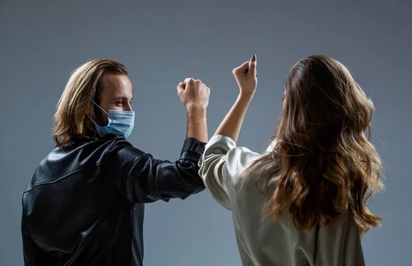 Two people bump elbows. Coronavirus epidemic. Friends in safety mask. Young couple wear face masks. Girl and guy greeting with elbows. New real life. Coronavirus quarantine. Elbows bump