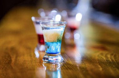 İçki bardaklarında alkollü içecekler. Tekila shot, votka, viski. Shot bardaklarında alkollü kokteyller. Kulüpte renkli şutlar. Alkolik içecekler farklı renklerdedir. Bardaki içkiler.