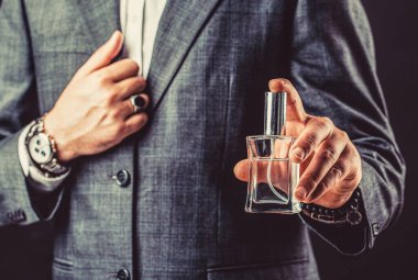 Perfume or cologne bottle and perfumery, cosmetics, scent cologne bottle, male holding cologne. Hand in with wrist watch in a business suit