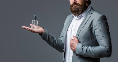 Erkek parfümü, parfüm. Erkeksi parfüm, takım elbiseli sakallı adam. Elinde parfüm şişesi tutan bir erkek.