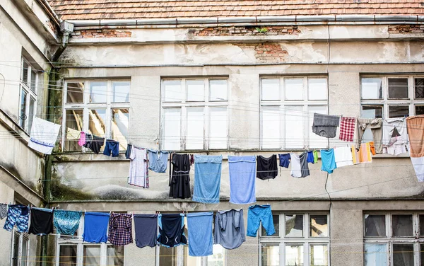 Fresh clean clothes are drying outside. Clothes hanging to dry on a clothes-line. Laundry dryings on the rope. Washed clothes drying outside of an old house. Washed clothes drying