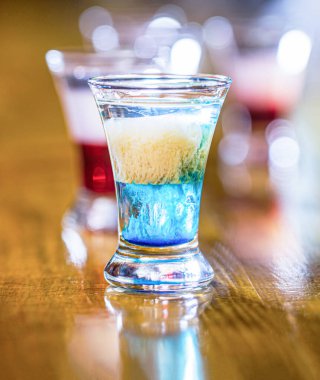 Kulüpte renkli şutlar. Alkolik içecekler farklı renklerdedir. Bardaki içkiler. İçki bardaklarında alkollü içecekler. Tekila shot, votka, viski. Shot bardaklarında alkollü kokteyller.