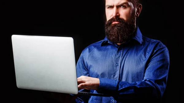 Hombre de negocios barbudo sosteniendo un ordenador en sus manos aislado sobre fondo negro. Joven hombre de negocios utilizando su ordenador portátil, pc —  Fotos de Stock