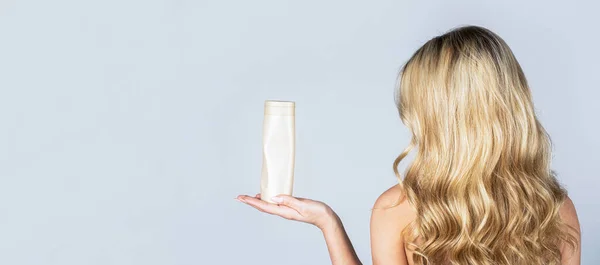 Frau mit Shampoo-Flasche. Schöne blonde Mädchen mit einer Flasche Shampoos in den Händen. Mädchen mit glänzendem und langem Haar. Frau lange Haare. Kopierraum — Stockfoto