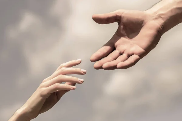 Giving a helping hand. Hands of man and woman on blue sky background. Lending a helping hand. Solidarity, compassion, and charity, rescue