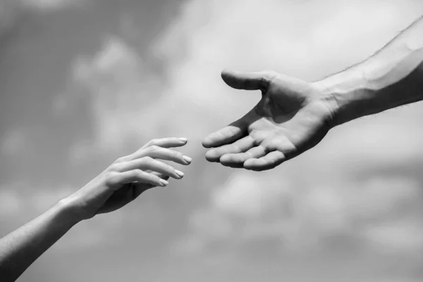 Solidarity, compassion, and charity, rescue. Hands of man and woman reaching to each other, support. Giving a helping hand. Lending a helping hand. Black and white