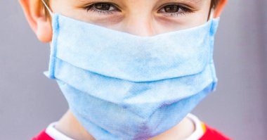 Cerrahi bandajlı bir çocuk. Tıbbi maskeli bir çocuk. Karantina ve koruma virüsü. Coronavirus karantinası. Dışarıda ilaç maskesi takan bir çocuk. Coronavirüs salgını. Yüz maskesi takan çocuk