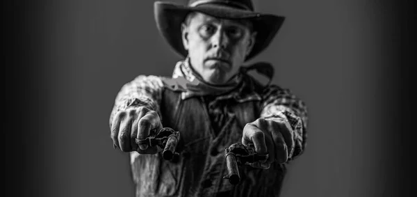 Man wearing cowboy hat, gun. West, guns. Portrait of a cowboy. Cowboy with weapon on background. Black and white — Foto de Stock