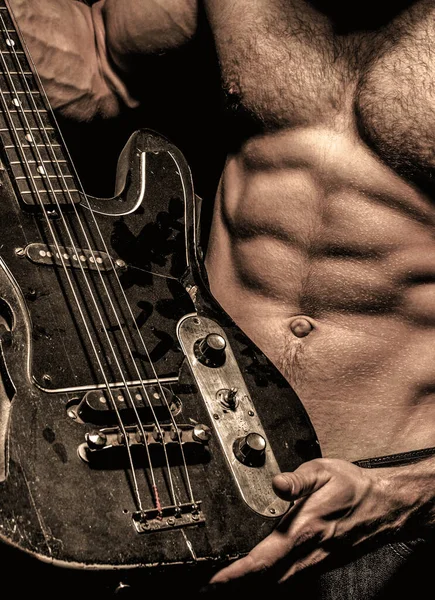 Electric guitar. Guitar. Instrument on stage and band. Strong, muscular, muscles man, bodybuilding. Music concept. Torso man. Play the guitar.