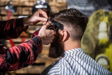 Berber saç makasıyla çalışıyor. Hipster müşteri saçını kestiriyor. Saç makasıyla berberin elleri, yaklaşın. Berber dükkanındaki sakallı adam. Saç kesimi konsepti. Berber dükkanında kuaförü ziyaret eden bir adam.