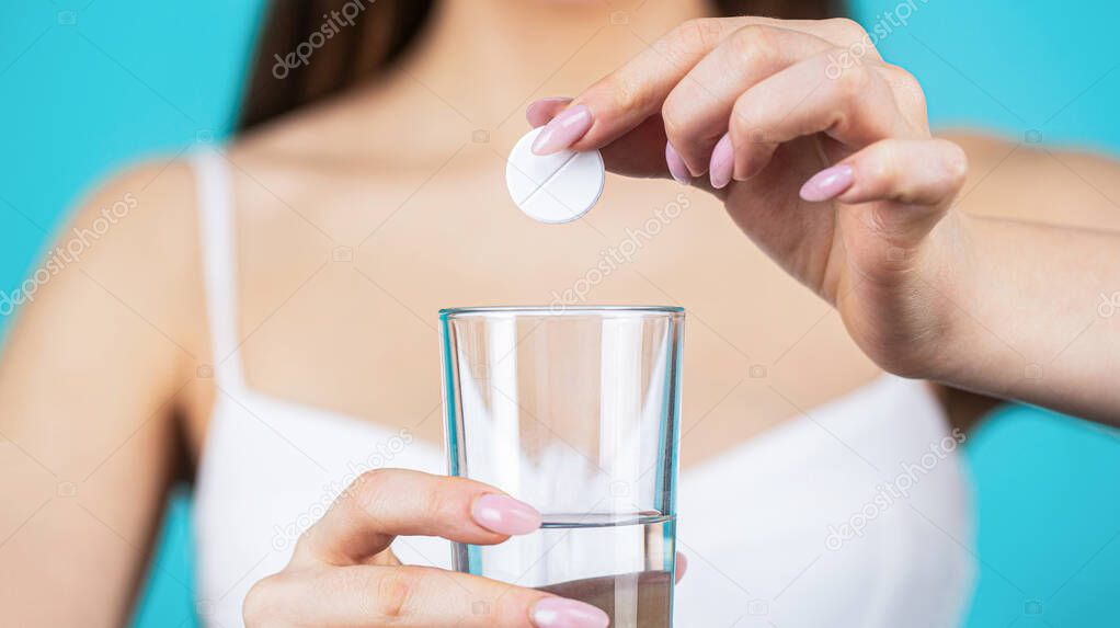 Taking a pill with a glass of water. Woman taking drugs to relieve headache. Take some pills, holds glass of water. Young woman taking pill against headache