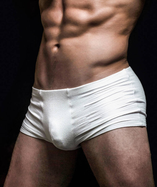 Человек в белых шортах. Красивый мускулистый мачо в белых трусах