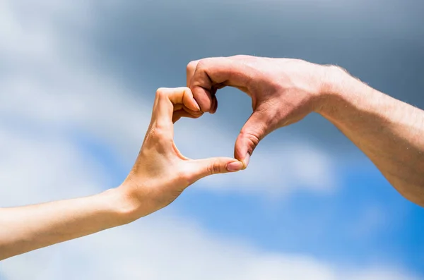 Female and man hands in the form of heart against the sky. Hands in shape of love heart. Heart from hands on a sky background. Girl fnd male hand in heart form love blue sky. Love, friendship concep — Foto de Stock