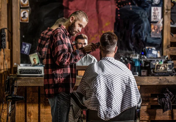 Homem barbudo na barbearia. Conceito de corte de cabelo. Homem visitando cabeleireiro na barbearia. Barbeiro trabalha com cortador de cabelo. Um cliente Hipster a cortar o cabelo. Mãos de barbeiro com cortador de cabelo, close-up — Fotografia de Stock