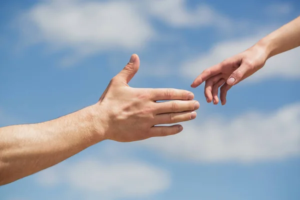 Segítő kezet nyújtok. Férfiak és nők kezei a kék ég hátterében. Segítő kezet nyújtok. Férfiak és nők keze nyújtózkodik egymás felé, támogatva őket. Szolidaritás, együttérzés és jótékonyság, mentés — Stock Fotó