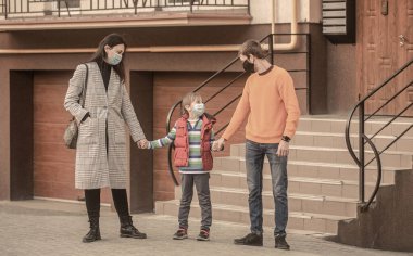 Coronavirus, hastalık, enfeksiyon, karantina, tıbbi maskeler, COVID-19. Annem ve babam yıpranmış maskelerle yürüyüşe çıktılar. Tıbbi maske takan aile