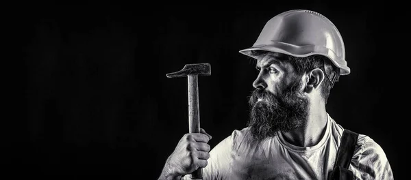 Handyman diensten. industrie, technologie, bouwer man, concept. Een man met baard, helm, helm, hoed. Hamer hameren. Bouwer in helm, hamer, klusjesman — Stockfoto