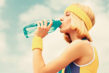Spor kızı arka plandaki bir şişeden su içiyor. Sağlıklı yaşam tarzı kavramı. Spor sırasında içmek. Koşudan sonra su içen genç kadın
