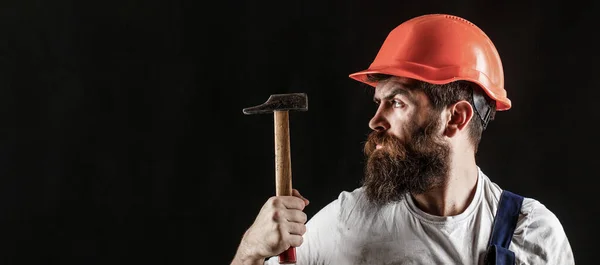 Handyman diensten. industrie, technologie, bouwer man, concept. Een man met baard, helm, helm, hoed. Hamer hameren. Bouwer in helm, hamer, klusjesman — Stockfoto