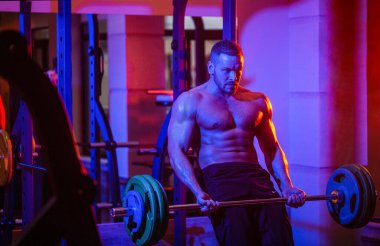 Altılı karın kaslı, atletik bir adam. Halterle antrenmanı bitir. Spor salonunda ağırlık kaldıran bir adam. Kapalı çekiş halterleri egzersizi. Spor salonunda çalış.