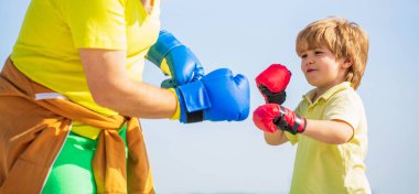 Koçla boks antrenmanında küçük bir çocuk. Küçük çocuk büyükbabasıyla boks egzersizi yapıyor. Baba oğluna boks eğitimi veriyor.
