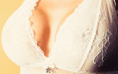 Sütyenini takan kızın göğüslerine yakın çekim. Şehvetli kadınlar, büyük göğüsler, büyük göğüsler. Seksi şehvetli kız. Beyaz sütyenli seksi kadın göğsüne yakın çekim. Estetik ameliyat. Seksi meme.