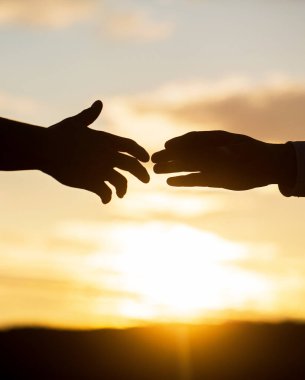 Kurtarma, el hareketlerine yardım etme. Gökyüzü arka planında iki el silueti, bağlantı ya da yardım kavramı. Uzanmış eller, kurtuluş, siluete yardım, konsept yardım. Yardım eli uzatıyorum.