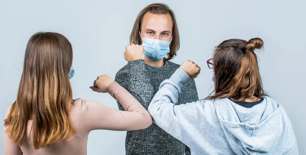 Elbows bump. People friends bump their elbows, coronavirus, social distance and friendship concept. Friends wearing protective face mask and greeting each other with the elbow