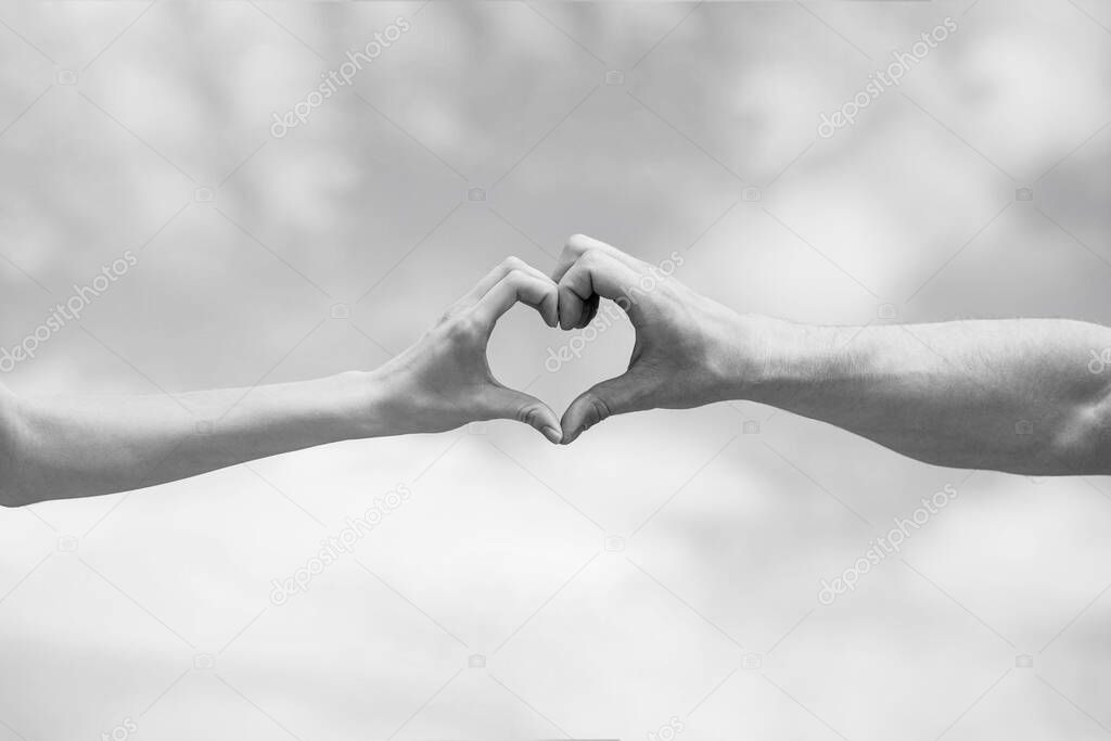 Female and man hands in the form of heart against the sky. Hands in shape of love heart. Heart from hands on a sky background. Black and white
