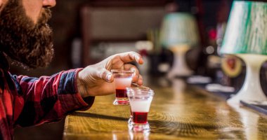 Bir gece kulübünde ya da barda shot bardaklarında alkol içmek. Sakallı adam kokteyl içerdi. Tekila shot, votka, viski, rom. Bardaki barmen. Tekila shot. Barda renkli kokteyller.