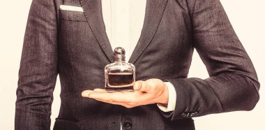 Parfüm, parfüm şişesi, parfüm, kozmetik, parfüm şişesi, erkek parfümü. Erkek parfüm şişesi tutuyor. Beyaz arka planda izole edilmiş parfüm şişesi tutan takım elbiseli bir adam.