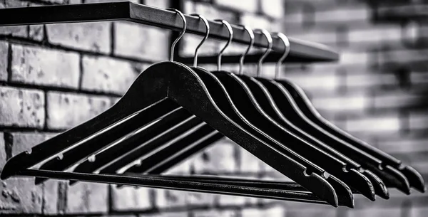 Fashionable different types of hanger. Wooden coat hanger clothes. Many wooden black hangers on a rod. Black and white — Stock Photo, Image