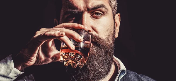 Boire du cognac barbu. Le sommelier a le goût de boire. Un homme tenant un verre de whisky. Siroter du whisky. Portrait d'homme à la barbe épaisse. Macho buvant. Dégustation, dégustation — Photo