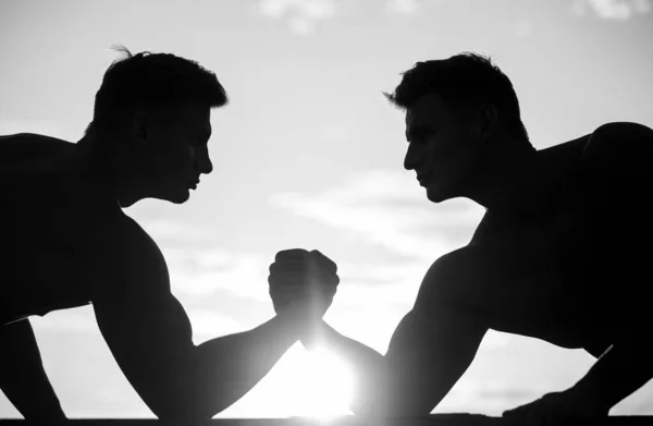 Rivalidad, vs, desafío, lucha libre. Atardecer, amanecer. Hombres midiendo fuerzas, brazos. Dos hombres luchando por el brazo. Silueta de manos que compiten en fuerza. Blanco y negro — Foto de Stock