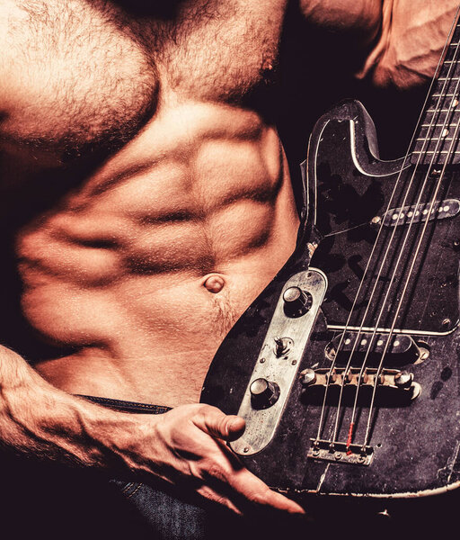 Music concept. Play the guitar. Chest muscles. Electric guitar. Torso man. Instrument on stage and band