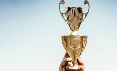 Şampiyonların altın kupaları vardır. Elinde spor kupası olan kişinin eli. Kazanan altın kupa. Profesyonel şampiyon. Kazanan takım, ödül.