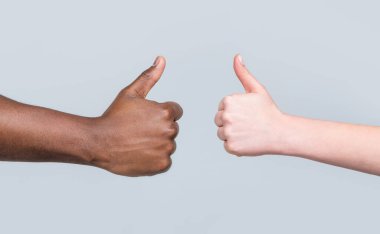 Jest gibi. Yakından çekilen el başparmaklarını gösteriyor. Kadın elleri baş parmağını kaldırıyor. Siyahların hayatı önemlidir. Destek desteği. Afrika erkek eli baş parmağını gösteriyor. Siyah ve beyaz eller birlikte görünüyor.